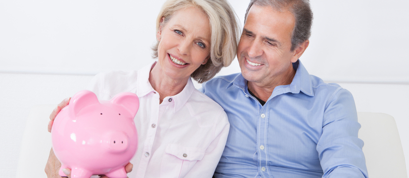 Senior couple smiling and holding a piggy bank