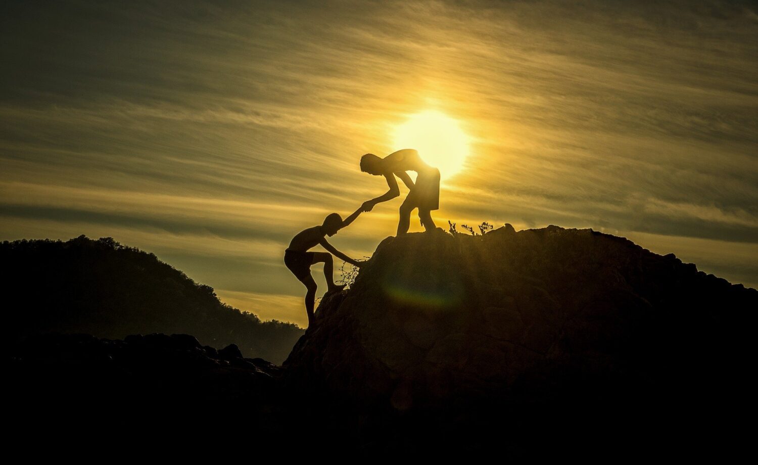 Climbing up a rock and one person helping the other get up