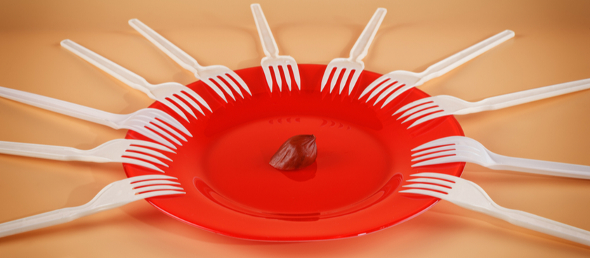 Red plate with 11 forks around the edges with a last piece of food in the middle of the plate