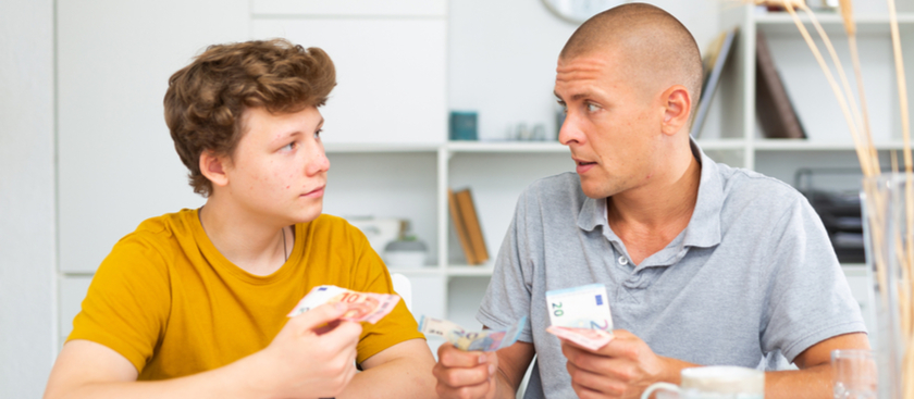 Dad and son talking with each other and holding Euros in their hands