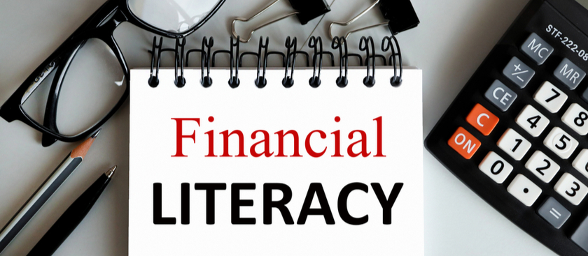 Financial Literacy written on notepad with calculator and glasses and pen to the side