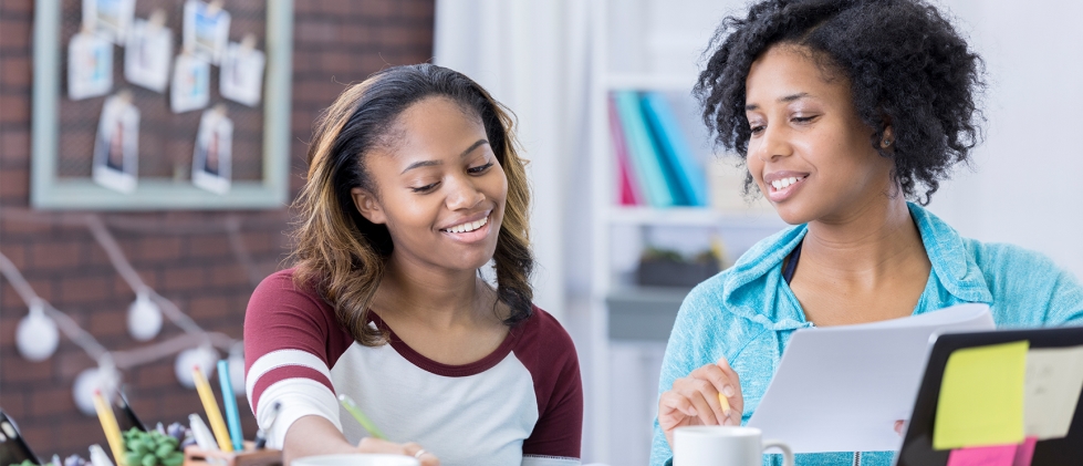 Mother and daughter together smiling teaching her about money