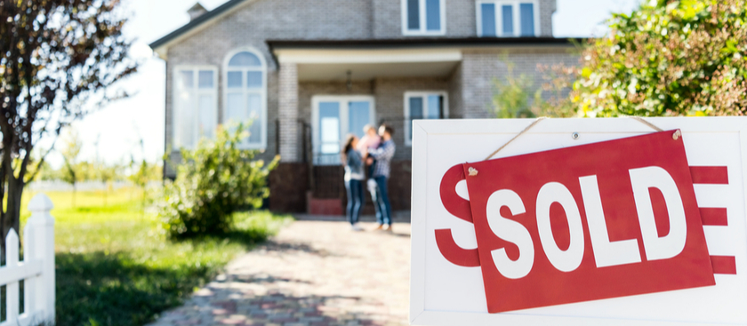 For sale sign with sold on it and family together in the background