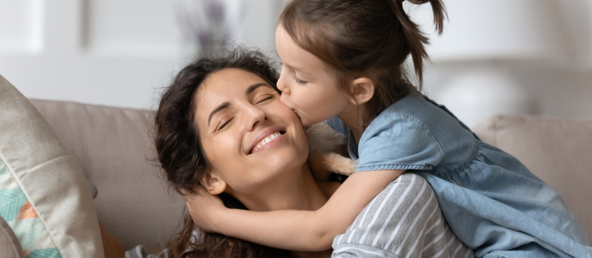 Daughter giving mom a kiss on the check