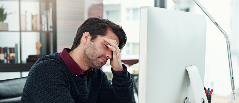Man at desk in Jacksonville stressed and holding his face