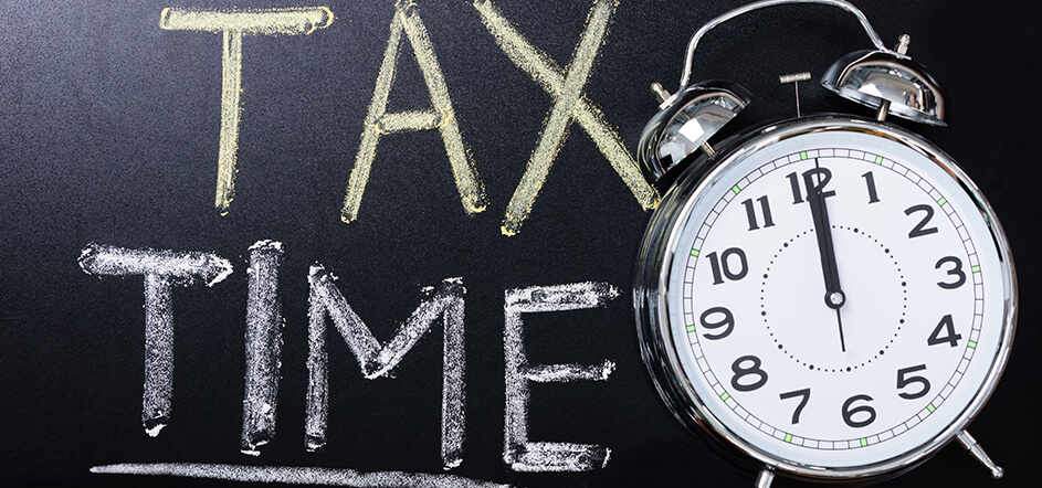 Chalk board that says tax time with a clock next to it