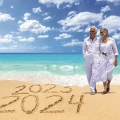 Seniors smiling together on the beach with 2024-2025 written in the sand