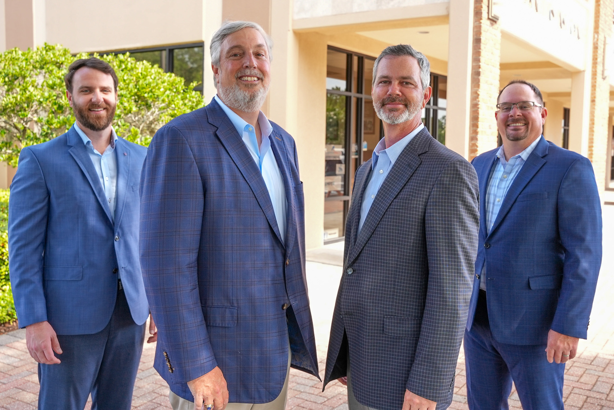 Davis Capital Team standing in a line with 2 on the left and 2 on the right facing each other wearing blue or gray blazers.