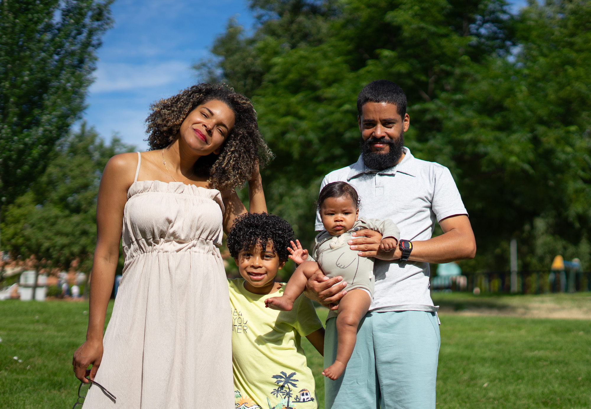 Portrait of a Latin family with afro hair of a mother, a father, a 7 year old boy and a 6 month old baby in a park